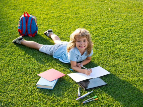 Child relax in the holiday. Kid read books on grass background