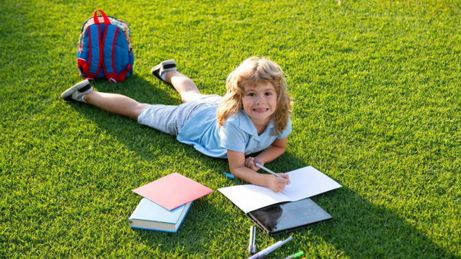 Child relax in the holiday. Kid read books on grass background