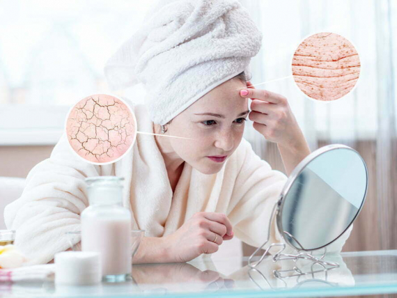 Beautiful young woman with a towel on her head looking at her dry skin with cracks and with first wrinkles. Circles increase the skin like a magnifying magnifier
