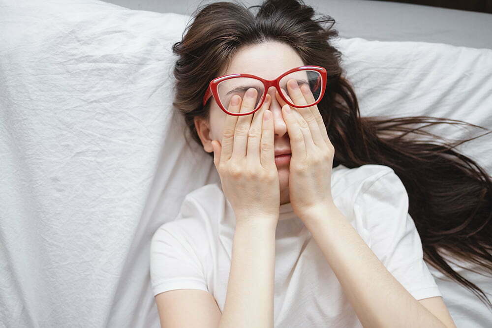 Young woman rubs her eyes after using glasses. Eye pain or fatigue concept, poor vision.